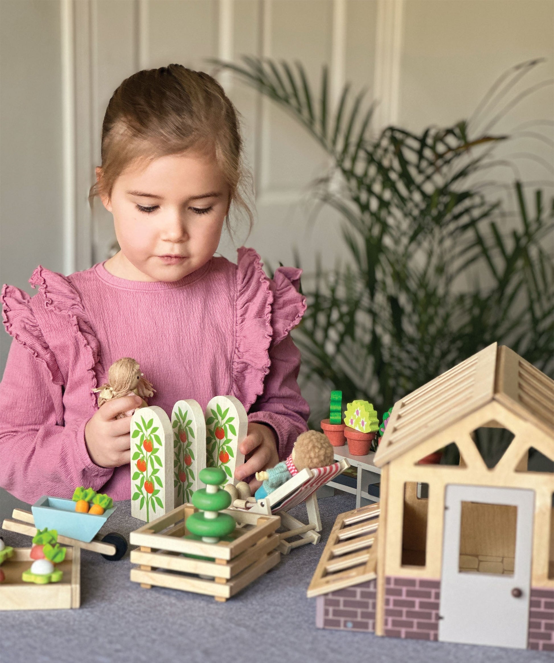 Scale shot of the wooden greenhouse next to a child's playroom floor