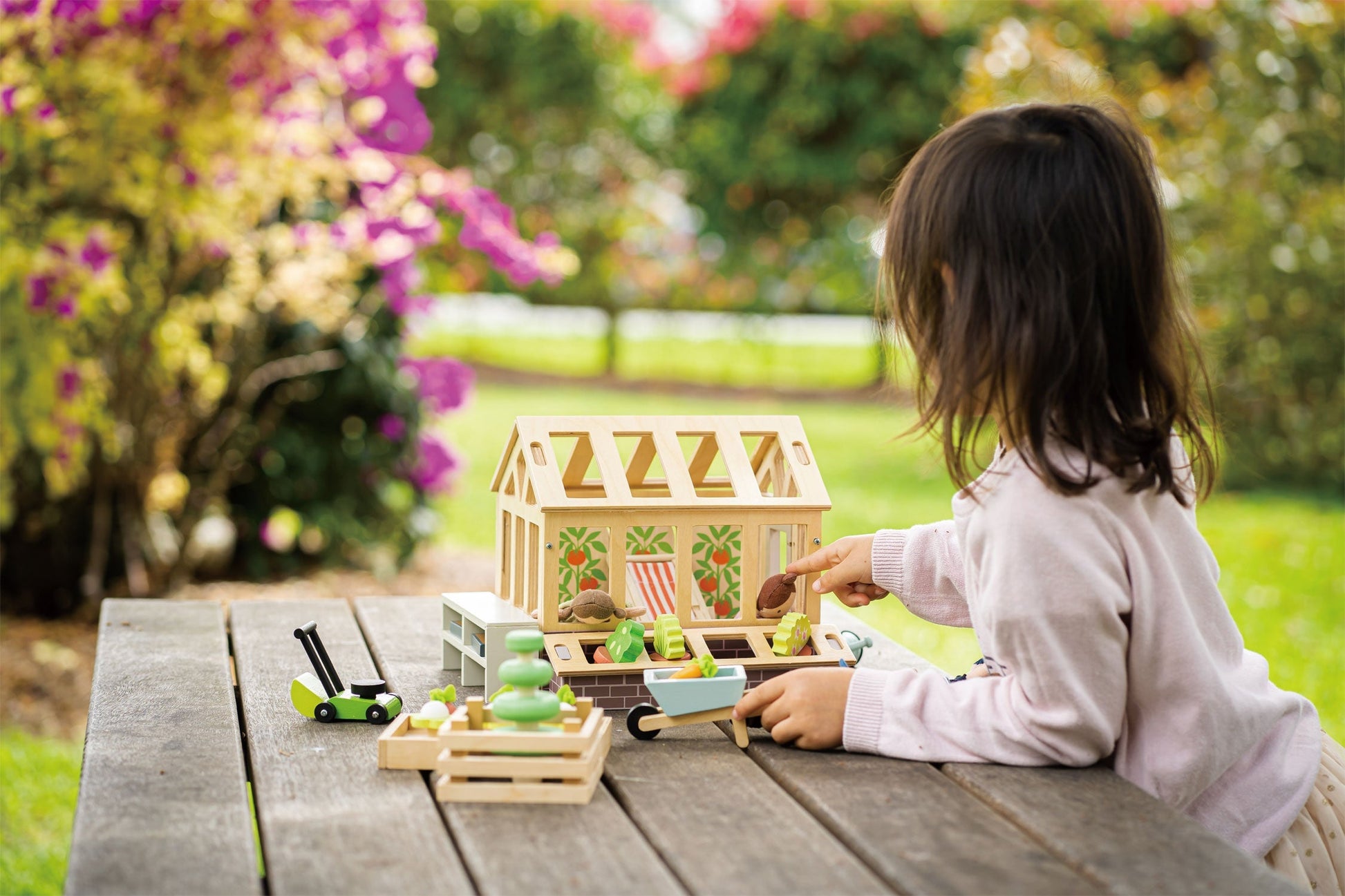 Storybook greenhouse with door open and wheelbarrow in front